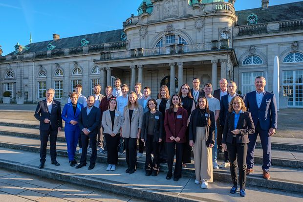 Gruppenfoto junger Erwachsener mit Ehrung vor historischem Bau