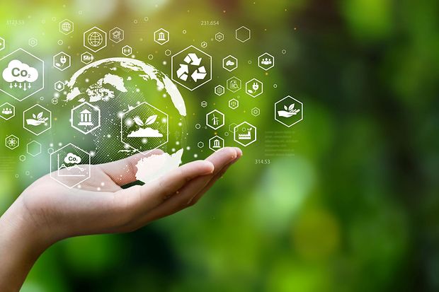 Symbol f&uuml;r Nachhaltigkeit: Hand h&auml;lt digitale Welt mit Umweltsymbolen