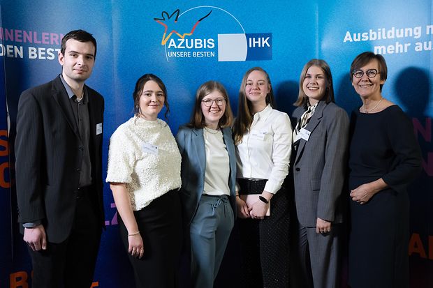 IHK-Gesch&auml;ftsf&uuml;hrerin mit f&uuml;nf bundesbesten Auszubildenden vor einer blauen Fotowand mit Aufschrift "Azubis. Unsere Besten"