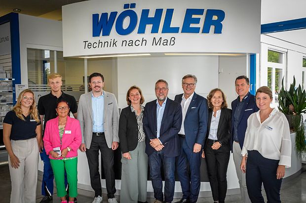Besuchsgruppe steht gemeinsam vor dem Logo der Firma W&ouml;hler im Eingangsbereich