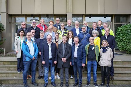 Gruppenfoto eines Ausschusses vor einem Geb&auml;ude mit rund 25 Personen.
