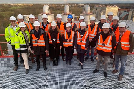 Gruppe in Warnwesten und Helmen bei einem Au&szlig;entermin auf einem Industriedach