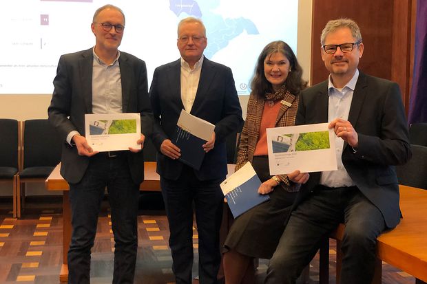 Vier Personen pr&auml;sentieren Ergebnisse der Standortumfrage Harsewinkel 2022, zwei halten Brosch&uuml;ren mit Titelseite in die Kamera.