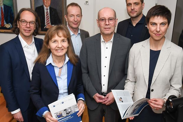 Sechs Personen in Businesskleidung stehen nebeneinander und zeigen Brosch&uuml;ren zum Handelsreport Ostwestfalen-Lippe 2022/23