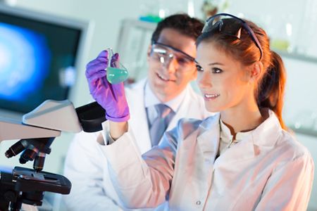 Ein Chemiker und eine Chemikerin untersuchen eine Fl&uuml;ssigkeit im Labor