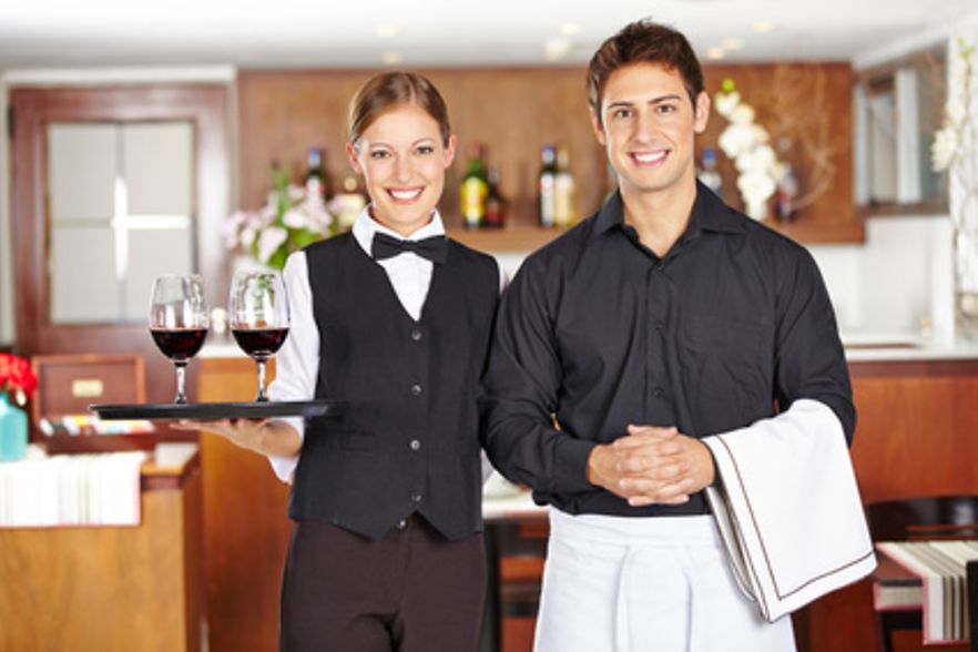 Kellner und Kellnerin l&auml;chelnd im Restaurant