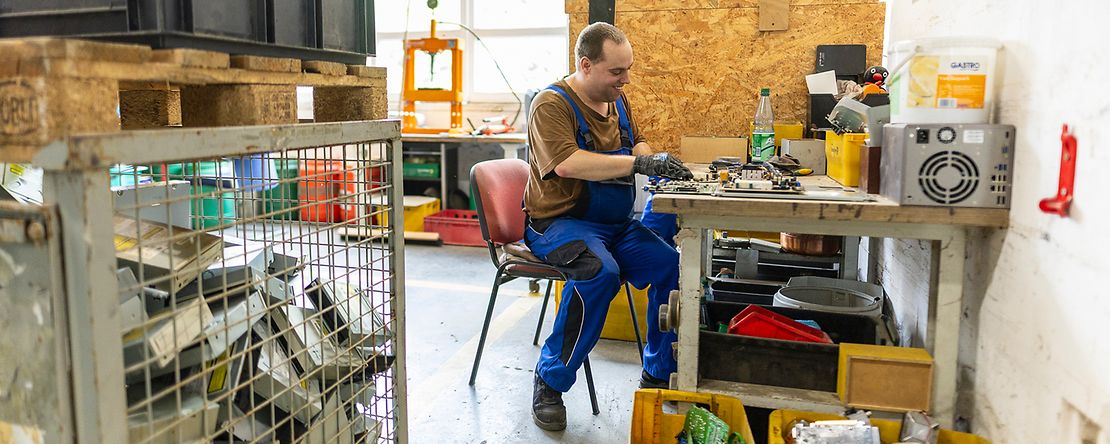 Mitarbeiter eines Recyclingunternehmens zerlegt einen ausrangierten Rechner