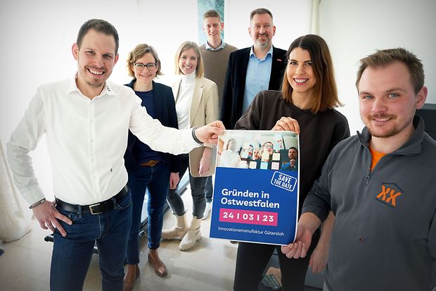 Sieben Personen halten ein Poster zur Veranstaltung &bdquo;Gr&uuml;nden in Ostwestfalen&ldquo;.