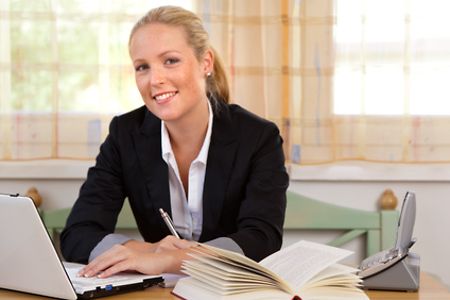 L&auml;chelnde junge Gesch&auml;ftsfrau am Arbeitsplatz