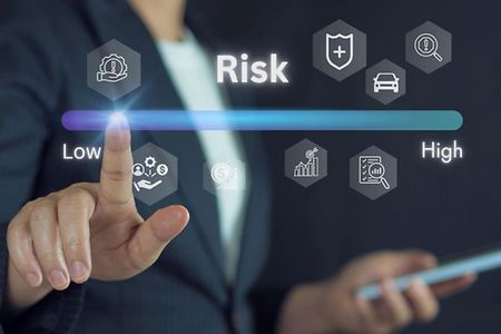 Person tippt auf eine digitale Skala von &bdquo;Low&ldquo; bis &bdquo;High&ldquo; unter dem Wort &bdquo;Risk&ldquo;