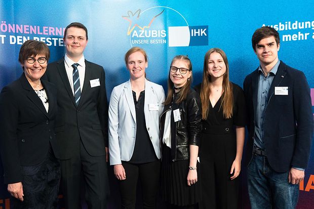 Sechs Personen stehen vor einer blauen Wand mit dem Logo &bdquo;Azubis &ndash; Unsere Besten&ldquo; bei einer IHK-Auszeichnungsveranstaltung.