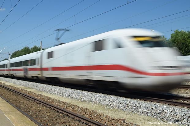ICE-Zug f&auml;hrt mit hoher Geschwindigkeit an einem Bahnsteig vorbei.