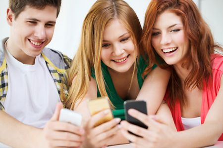 Drei l&auml;chelnde Jugendliche mit Smartphones