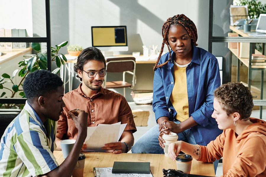Group of young employees gathered by table in office