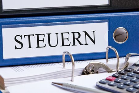 Taschenrechner, Stift und Aktenordner mit Aufschrift Steuern