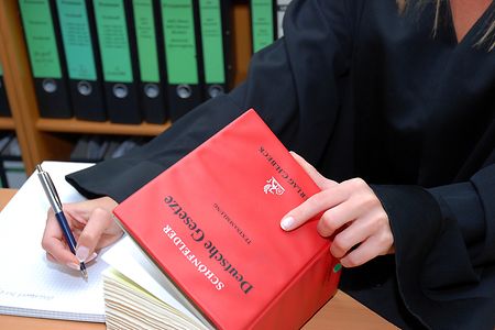 Rechtsanw&auml;ltin mit Gesetzbuch beim Schreiben