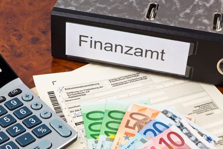Taschenrechner, Geldscheine, Aktenordner mit der Aufschrift Finanzamt und Unterlagen