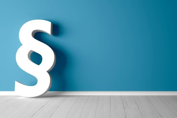 Wei&szlig;es Paragraphenzeichen lehnt an blauer Wand.