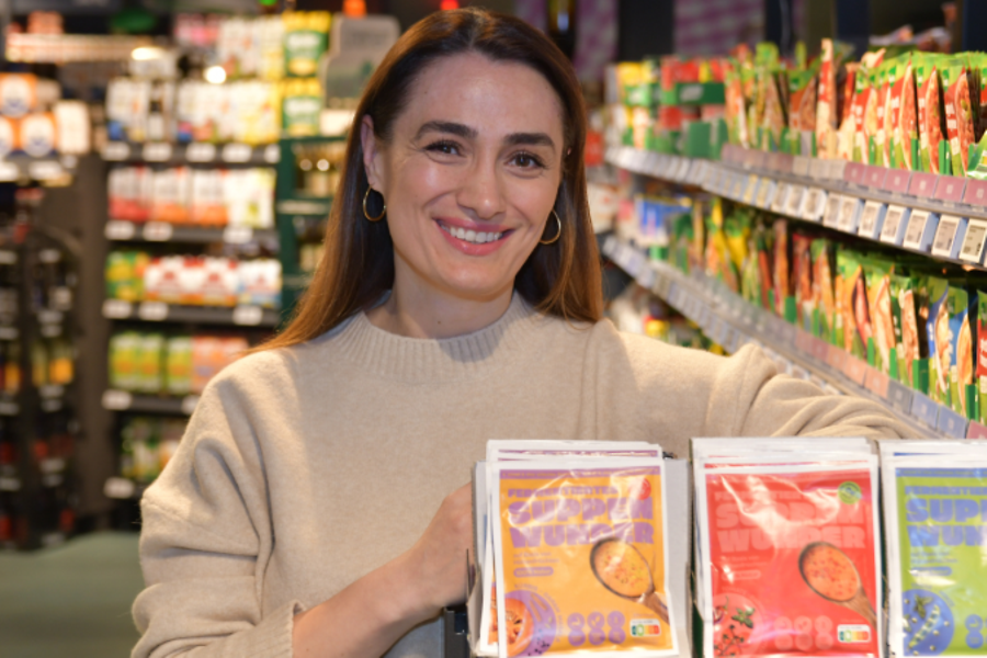 Frau lächelt vor Supermarktregal mit bunten Verpackungen.