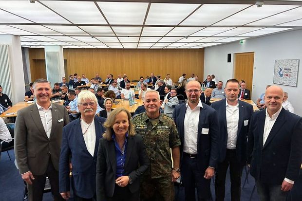 Gruppenfoto von Bundeswehr und Wirtschaft vor Publikum.