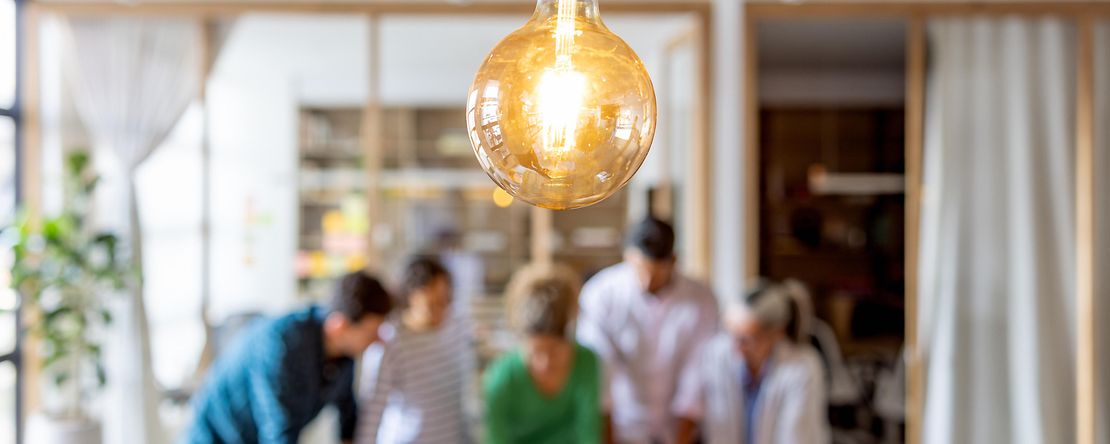 Gruppe lateinamerikanischer Gesch&auml;ftsleute beim Brainstorming im B&uuml;ro &ndash; Fokus auf Gl&uuml;hbirne