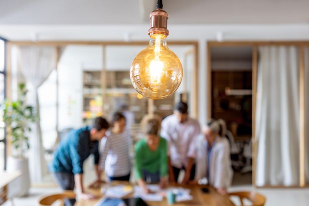Gruppe lateinamerikanischer Gesch&auml;ftsleute beim Brainstorming im B&uuml;ro &ndash; Fokus auf Gl&uuml;hbirne