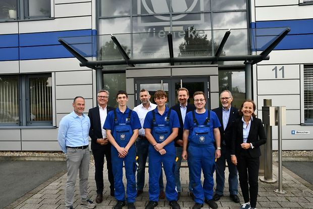 Gruppe von Auszubildenden und Unternehmensvertretern vor einem Firmengeb&auml;ude