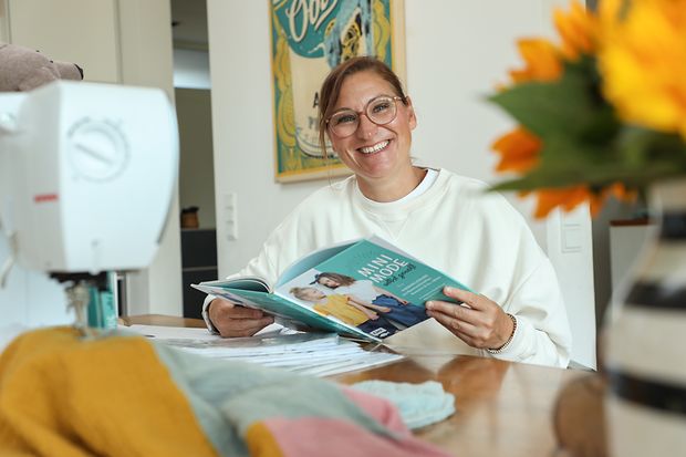 Anja F&uuml;rer sitzt an einem Tisch und h&auml;lt ein Buch. 