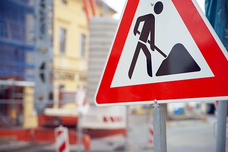 Nahaufnahme eines Baustellenschildes mit rotem Rahmen und schwarzem Piktogramm