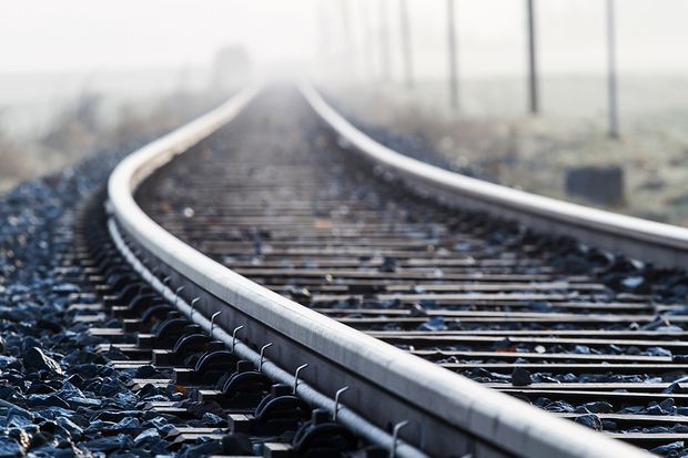 Nahaufnahme von Bahnschienen, die sich in der Ferne im Nebel verlieren.