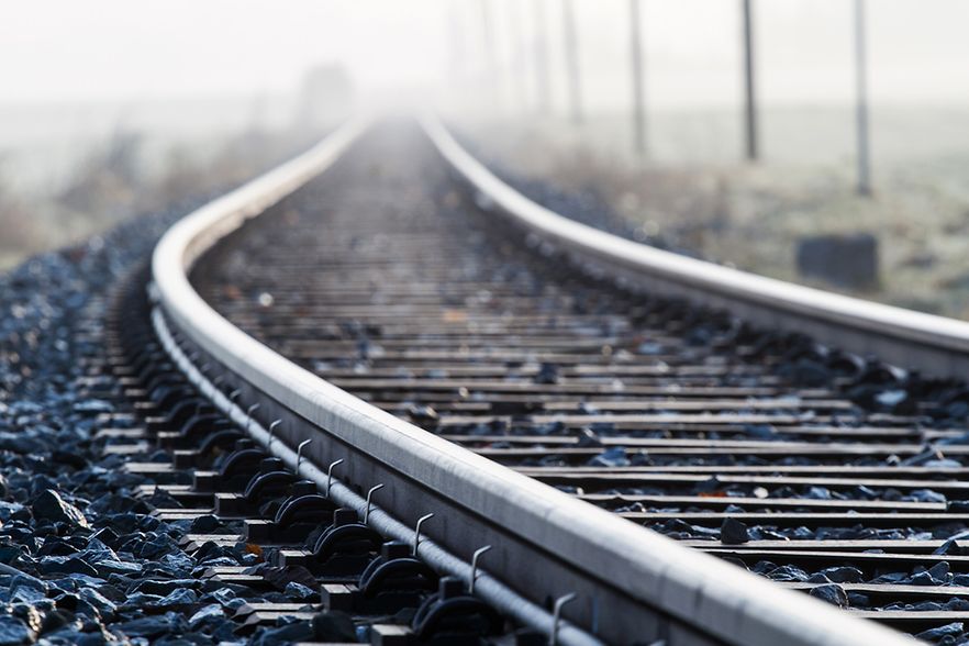Nahaufnahme von Bahnschienen, die sich in der Ferne im Nebel verlieren.