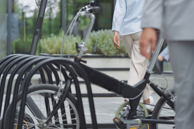 Fahrrad im St&auml;nder, Passanten im Hintergrund.