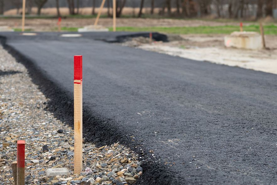 Frisch asphaltierte Stra&szlig;e mit Markierungspfosten in einem Baugebiet
