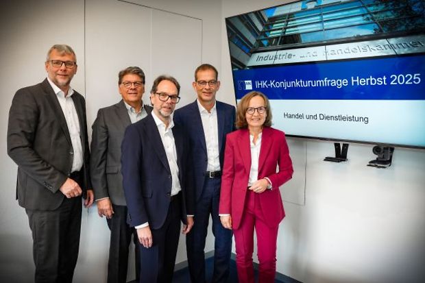 F&uuml;nf Personen stehen vor einem Bildschirm mit der Aufschrift &bdquo;IHK-Konjunkturumfrage Herbst 2025".