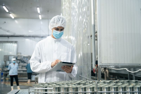 Mitarbeiter in Schutzkleidung pr&uuml;ft Produktion.