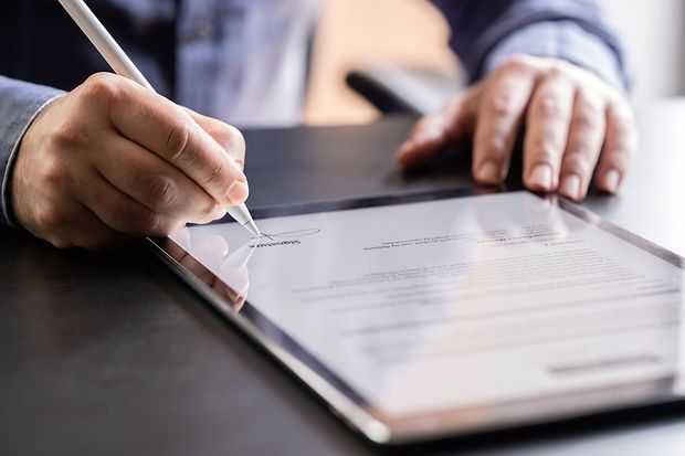 Mann unterschreibt digital auf einem Tablet