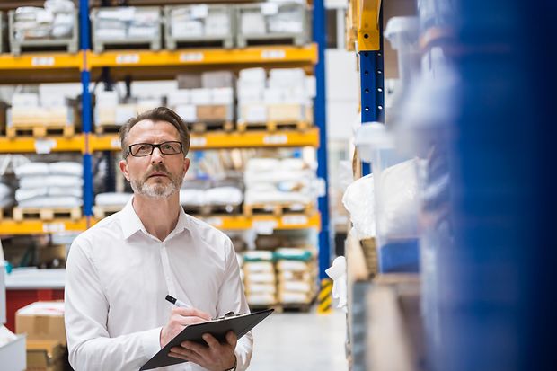 Man in storehouse taking notes