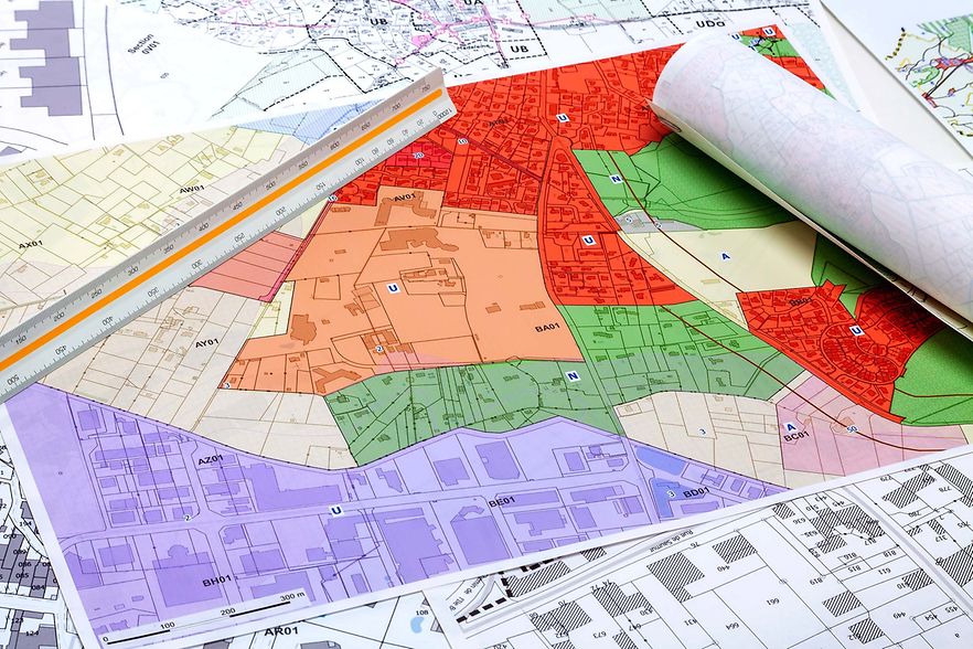 Farbig markierter Bebauungsplan mit Lineal und gerollten Planunterlagen