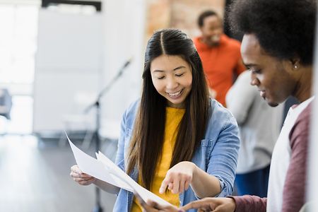 Two young adults reviewing documents together, smiling