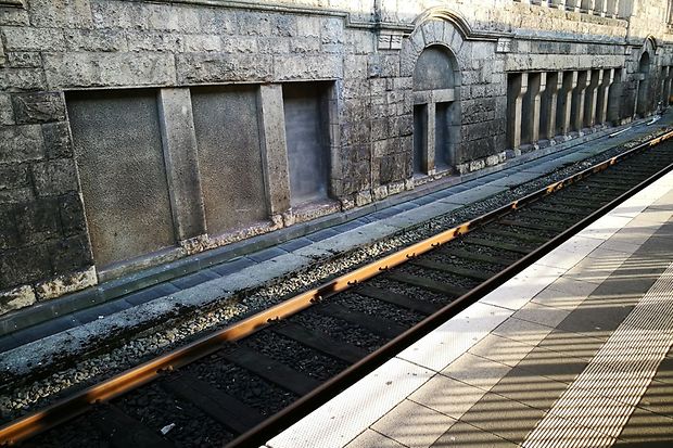 Gleise und Bahnsteig am Hauptbahnhof Bielefeld vor einer historischen Steinwand.