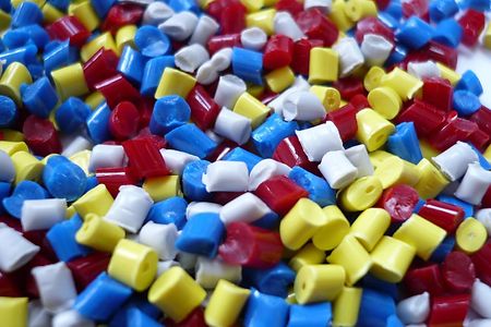 Bunte Kunststoffgranulat-Pellets in Rot, Blau, Gelb und Wei&szlig;.