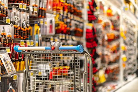 A shopping cart by a store shelf in a hardware store