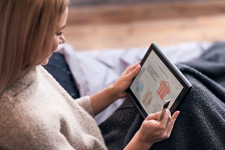 Joyful woman enjoying online shopping in bed