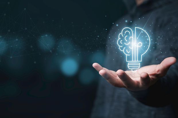 Hand h&auml;lt digitale Gl&uuml;hbirne mit Gehirn-Symbol als Zeichen f&uuml;r Innovation.