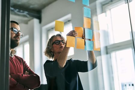 Businesspeople using sticky notes discussing strategies and brainstorming at office