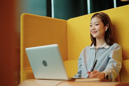 Asian woman on a video call discussing work at a co-working space