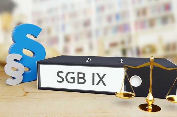 Aktenordner SGB IX mit Paragrafzeichen und Waage als Symbol f&uuml;r Recht und Inklusion
