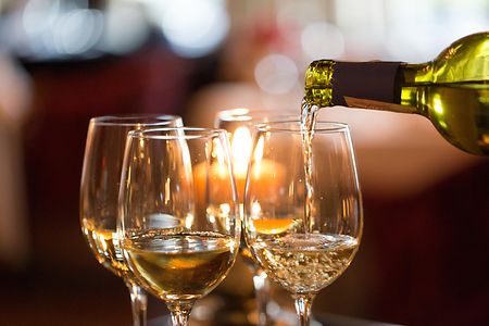 Jemand schenkt Wei&szlig;wein in Gl&auml;ser