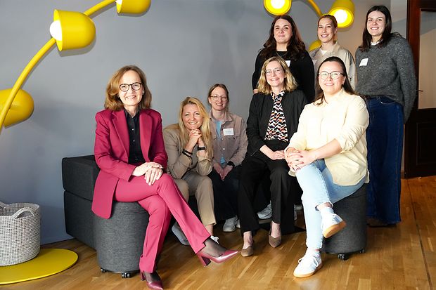 Gruppe von Frauen sitzt unter gelber Lampe in einem modernen Raum.