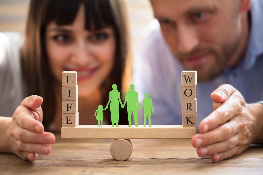 Eine Frau und ein Mann vor einer Wippe mit Holzkl&ouml;tzen mit den Aufschriften Life und Work
